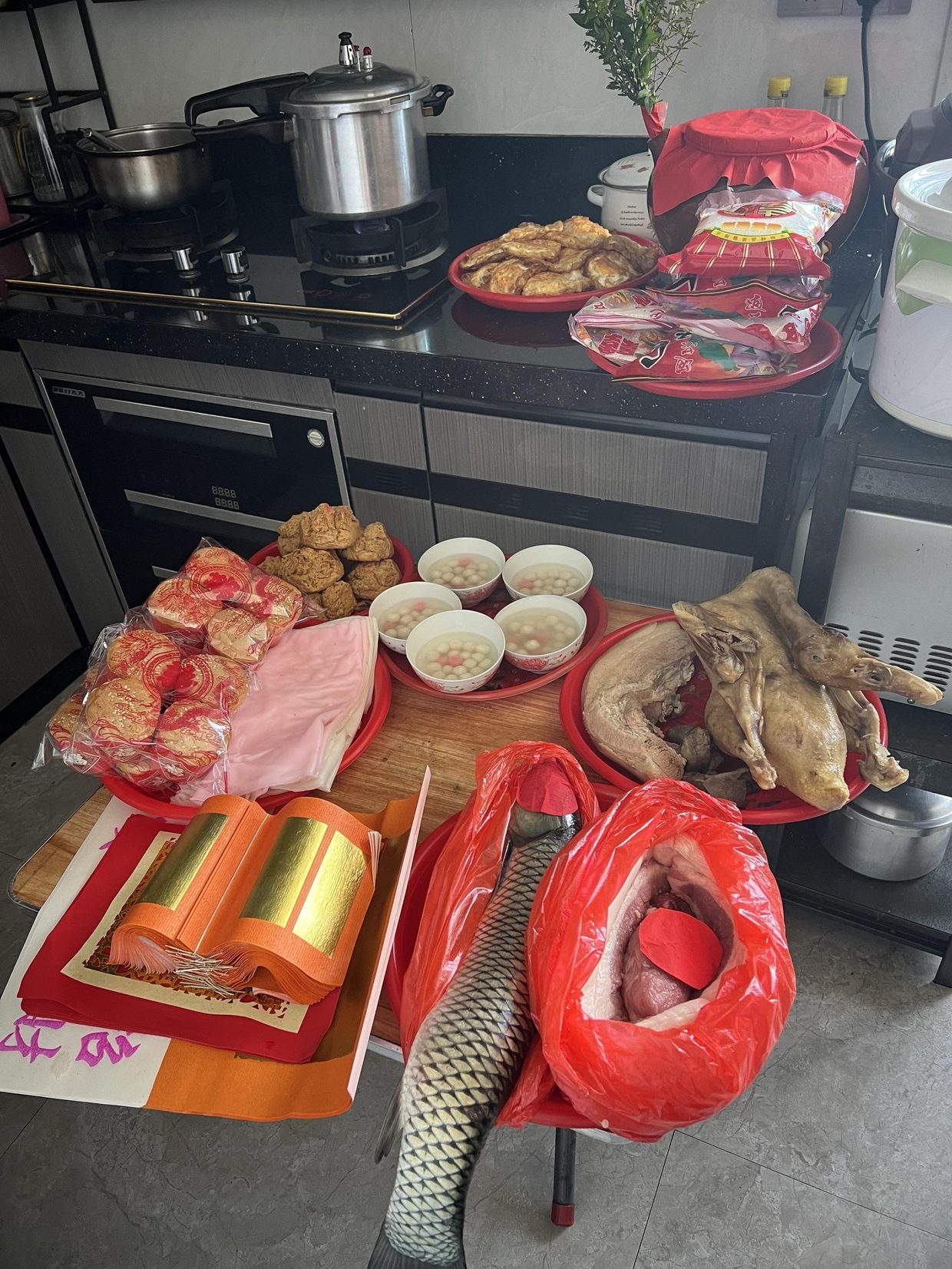 添丁的供桌：一只鸡、一方猪肉、一尾鱼、成摞红团、五碗甜汤与一叠金纸。图源：抖音 @萍JIE，10 月 13 日。