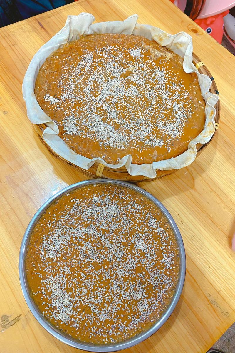 刚蒸好的甜粿，一笼垫布、一盘平底，面上撒了芝麻　图：抖音 @淼淼，2022 年 1 月 29 日